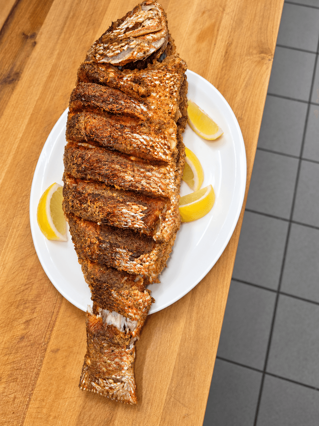 Poisson entier servi sur une planche de bois.