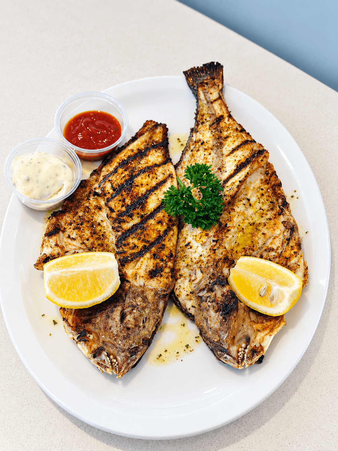 Poisson entier grillé servi avec citron et sauces.
